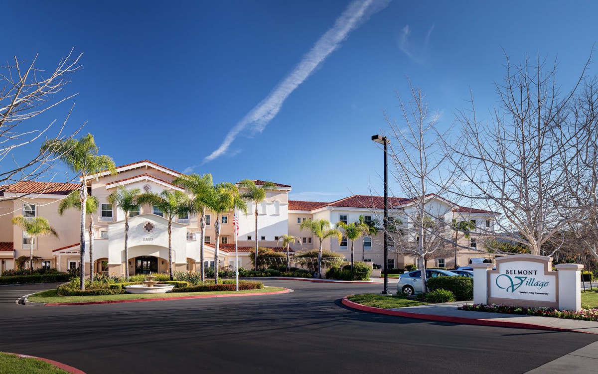 A residential building surrounded by palm trees under a clear blue sky.