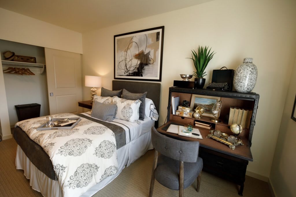 A cozy bedroom with a neatly made bed, a stylish desk, and modern decor.