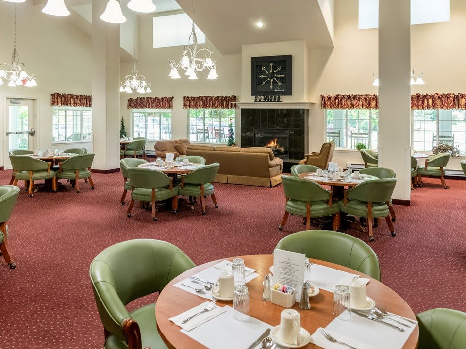 A spacious dining area with multiple tables and chairs, featuring a cozy interior design.