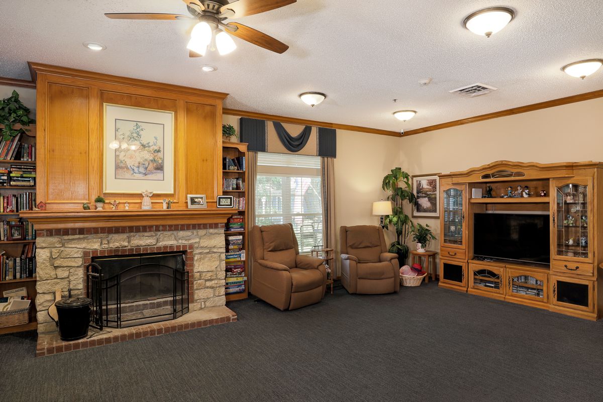 A cozy living room featuring a fireplace, armchairs, and a television.