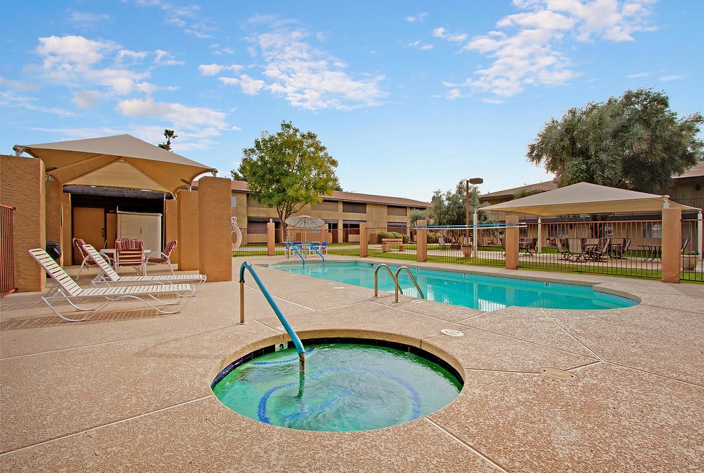 A sunny day at an outdoor pool and hot tub area in a resort.