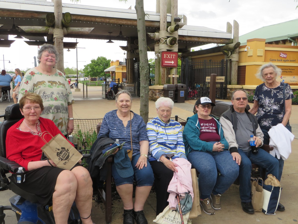 A group of people sit together on a bench outdoors.