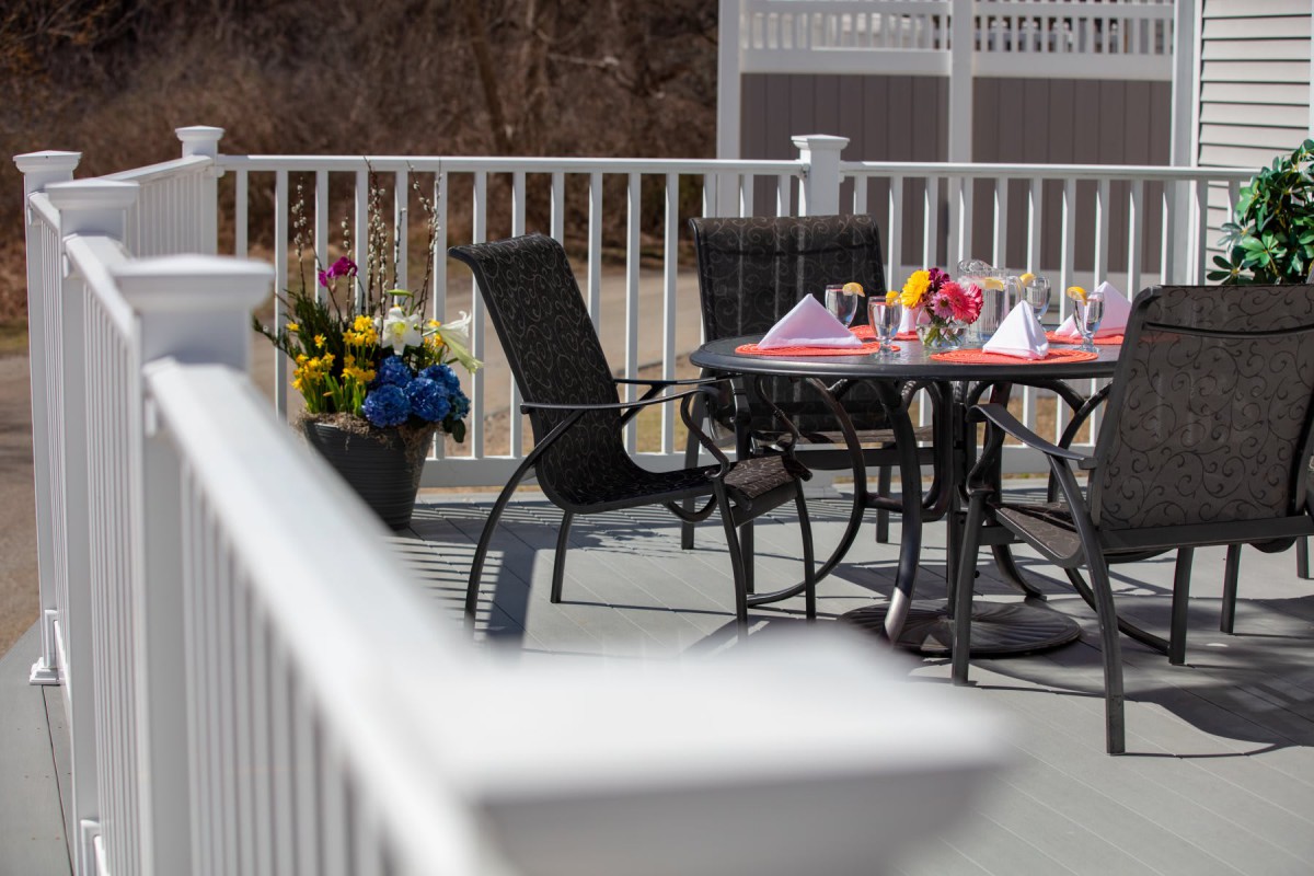 A patio setup with a table and chairs surrounded by flowers.