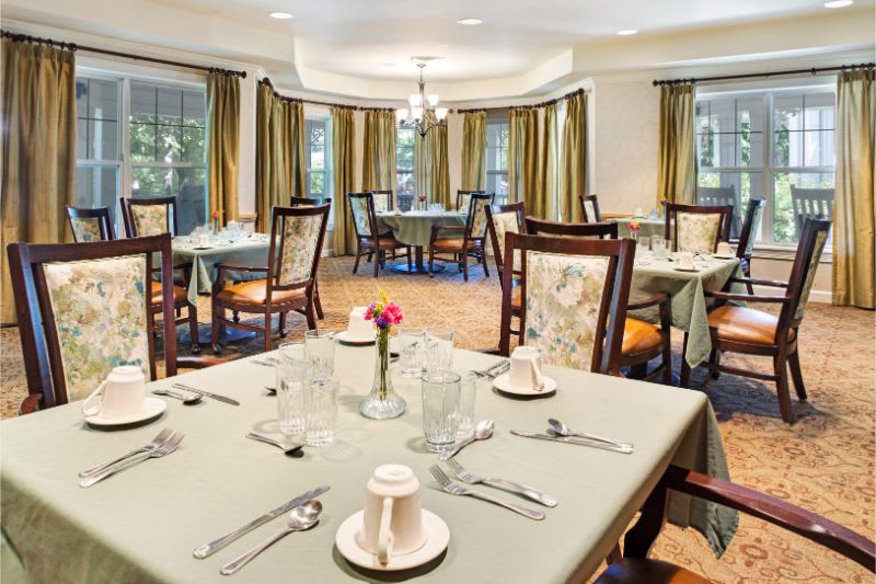 Elegant dining room with neatly arranged tables and chairs, set for a meal.