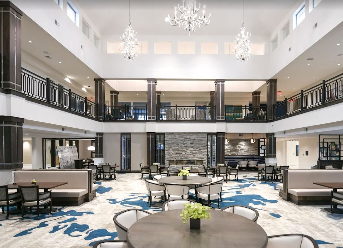 A modern and spacious lobby featuring chandeliers, multiple seating areas, and elegant decor.