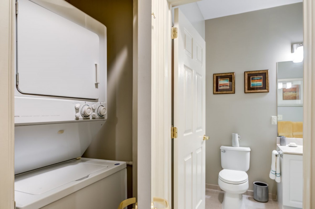 A compact home interior featuring a stacked washer and dryer next to a bathroom with a toilet.