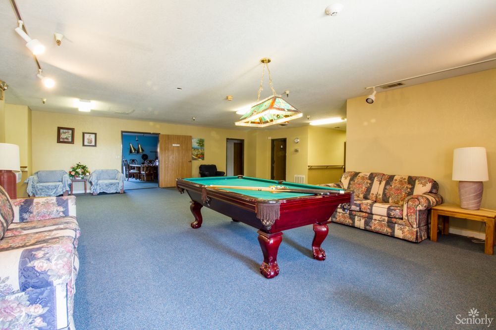 A spacious game room featuring a pool table and seating area.