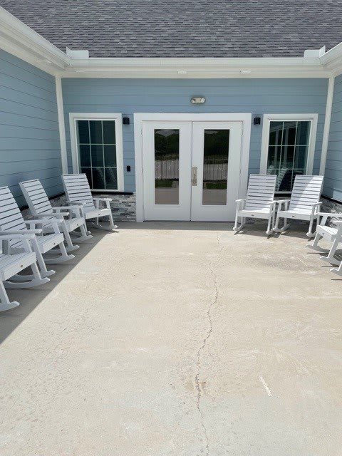 White rocking chairs arranged outside a building with double doors.