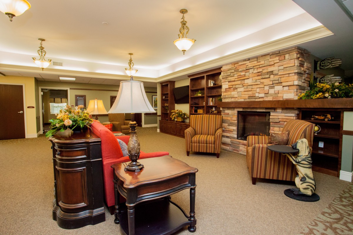 A cozy living room featuring a stone fireplace, comfortable armchairs, and built-in bookshelves.