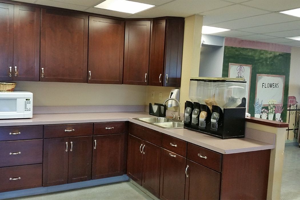 An office kitchen with wooden cabinets and a coffee machine on the countertop.