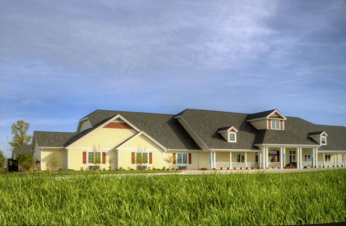 A spacious single-story house with a well-maintained lawn under a clear blue sky.