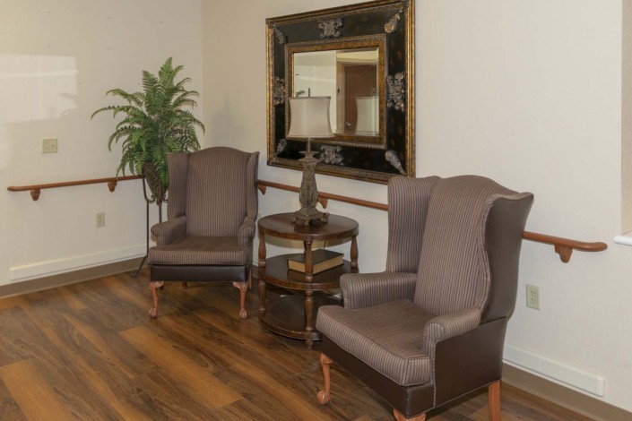 A cozy living room corner with two armchairs, a side table, and a decorative mirror.