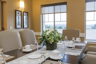 An elegantly set dining table with a floral centerpiece and neatly arranged dishes and glasses.