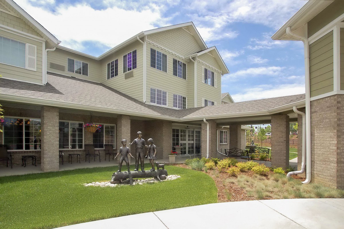 A residential building with a well-landscaped yard and a statue in front.