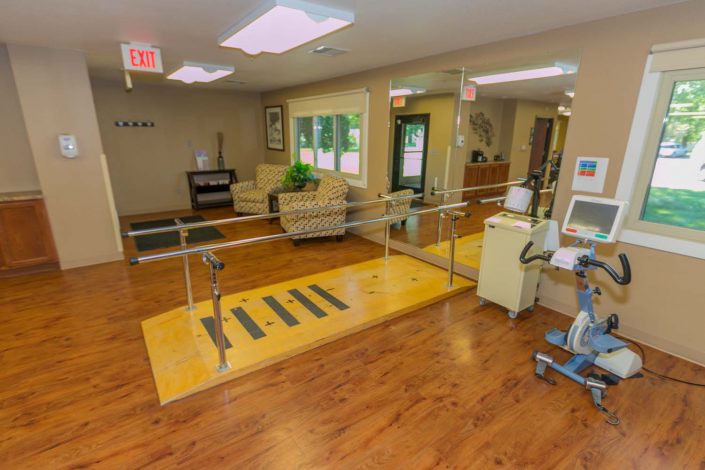 A physical therapy room equipped with parallel bars and exercise equipment.