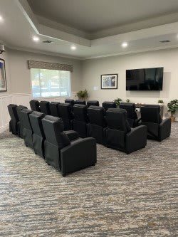 A modern home theater setup with multiple rows of comfortable seating facing a large screen.