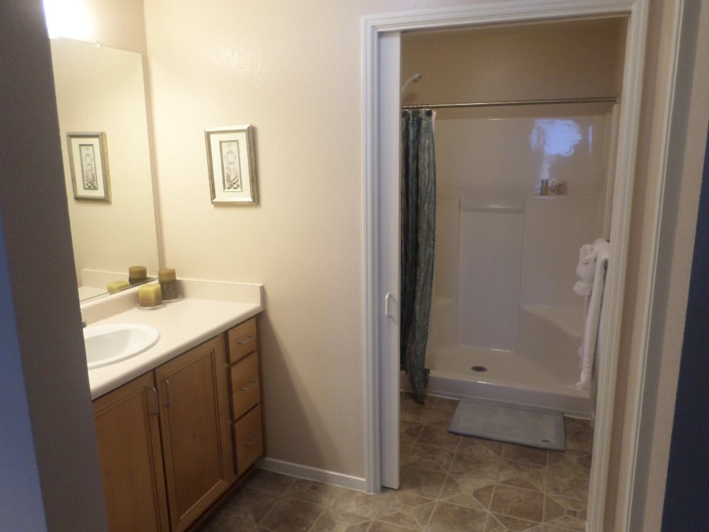 A clean and simple bathroom with a shower, sink, and wooden cabinets.