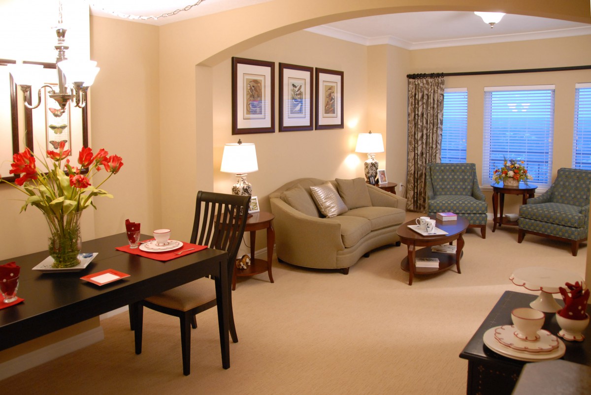 A cozy living room with a connected dining area, featuring comfortable furniture and warm lighting.