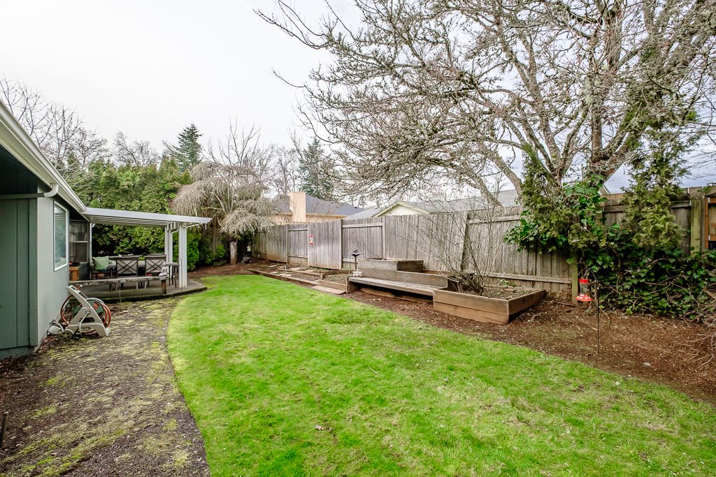 A serene backyard with a well-maintained lawn, wooden deck, and mature trees.