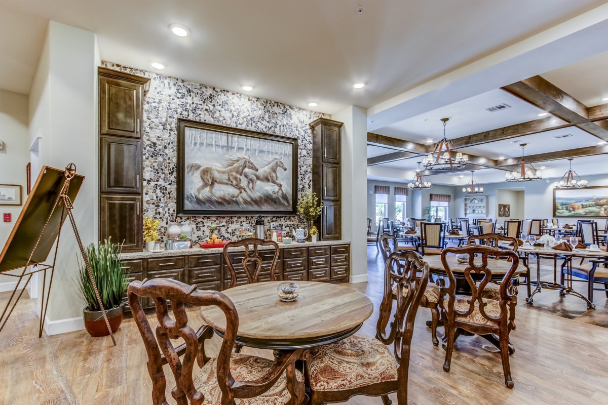 A luxurious dining room featuring elegant wooden furniture, a large artwork, and a chandelier.