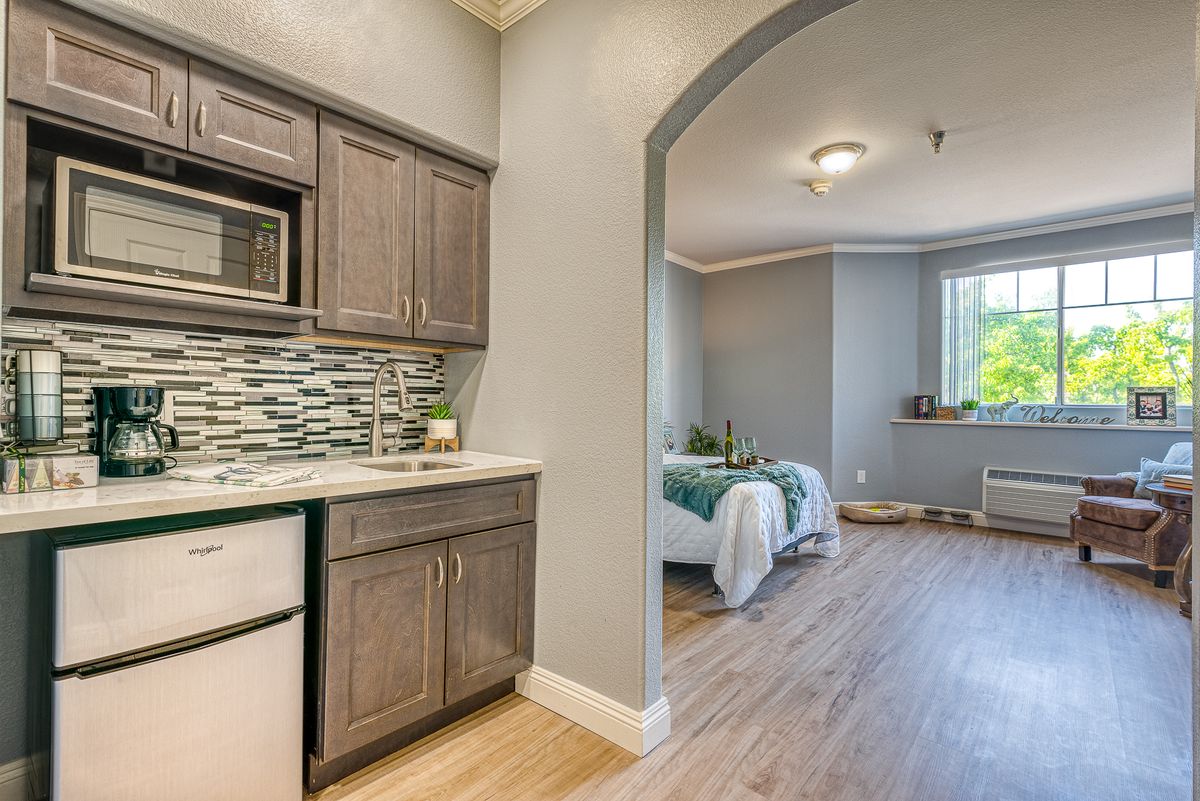 A modern apartment interior featuring a kitchen and adjacent bedroom.