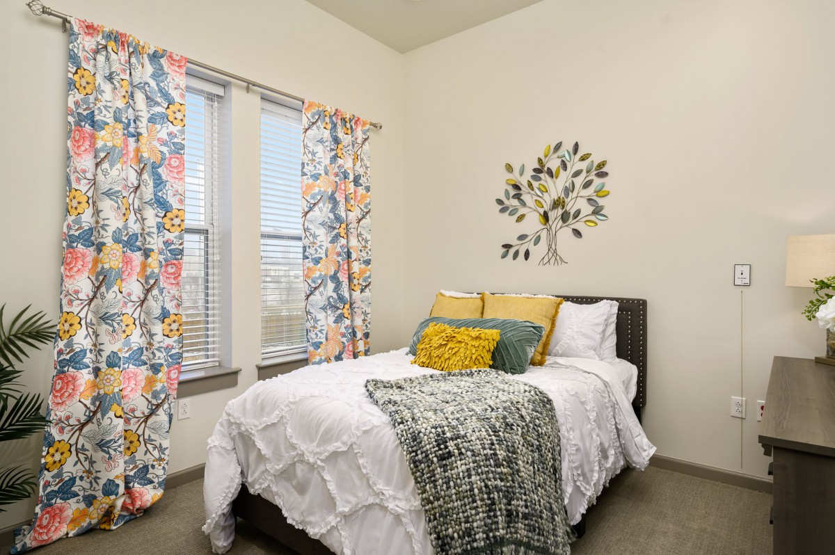 A cozy bedroom with colorful curtains and decorative pillows.