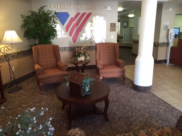 A welcoming lobby with two armchairs and a table, decorated with plants and patriotic wall art.