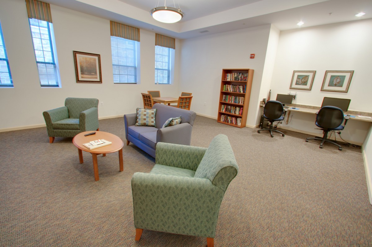 A cozy lounge area with comfortable seating, a bookshelf, and a computer desk.