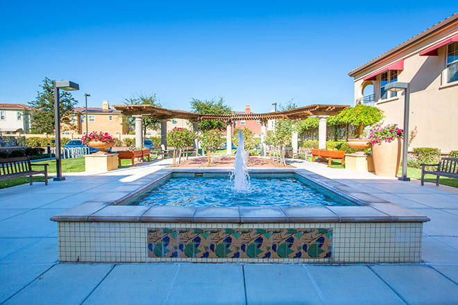 A beautiful courtyard with a central fountain and tiled design under a bright blue sky.
