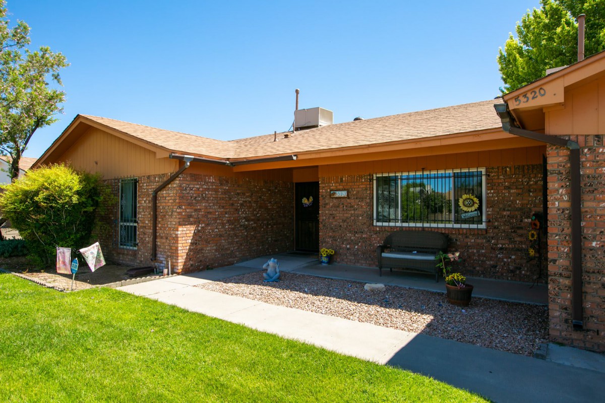 A single-story brick house with a well-maintained front yard on a sunny day.