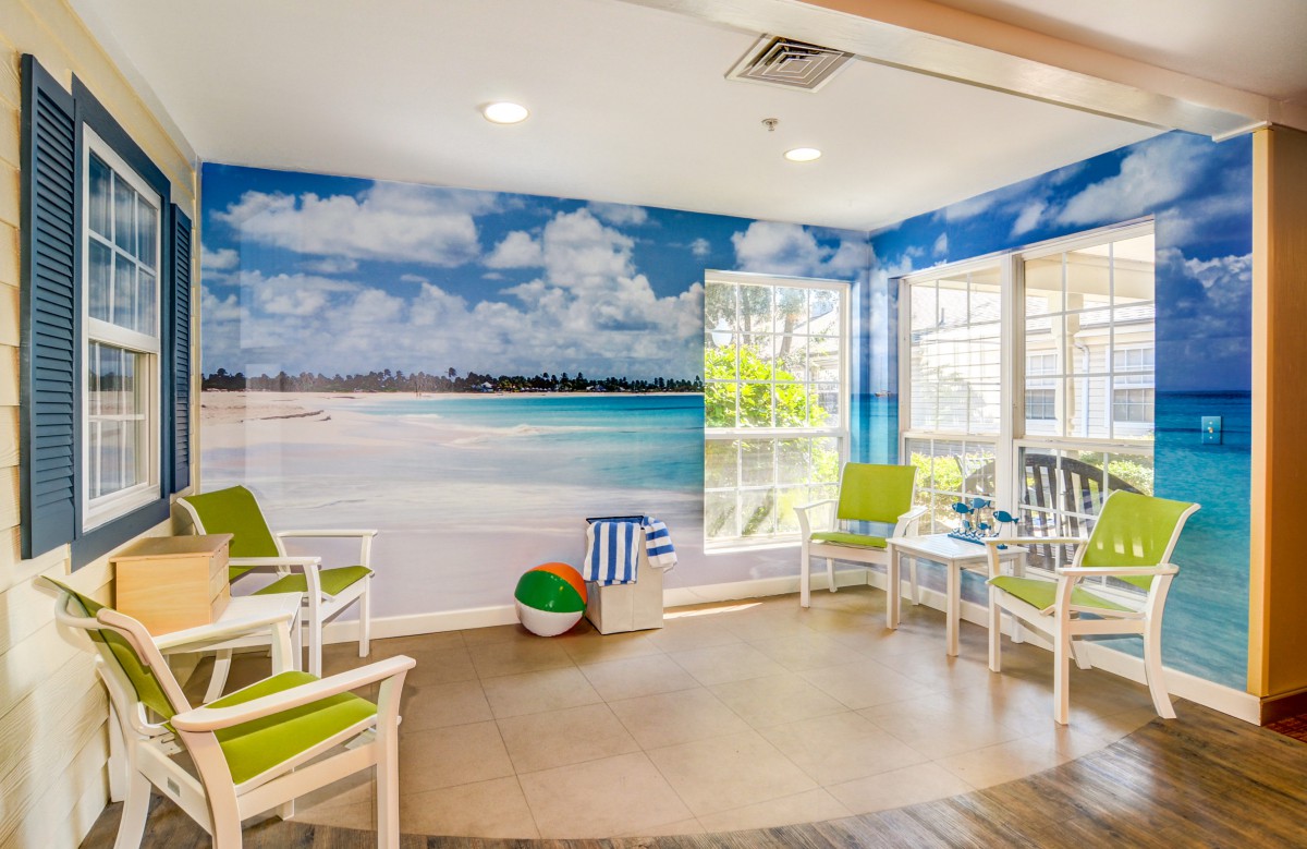 A relaxing waiting room with a tropical beach mural and cozy seating.