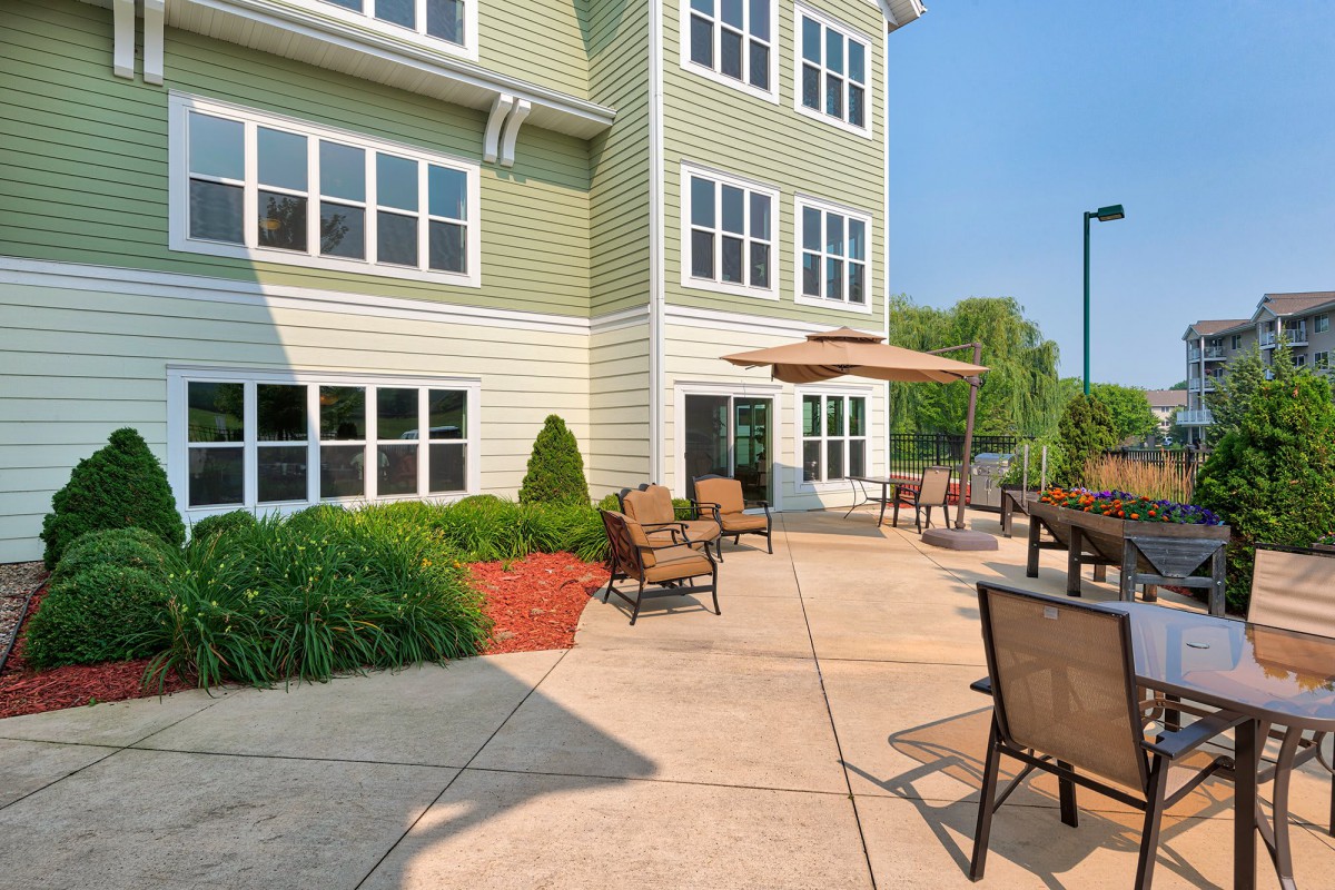 A sunny outdoor patio with seating and a view of a multi-story building.