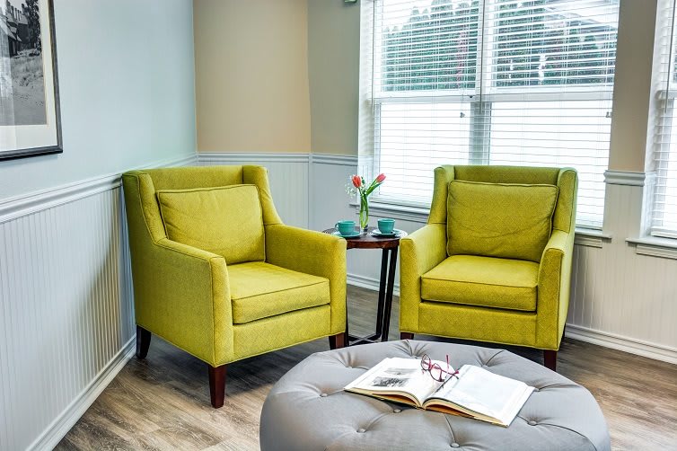 A cozy living room corner with two green armchairs and a round ottoman.