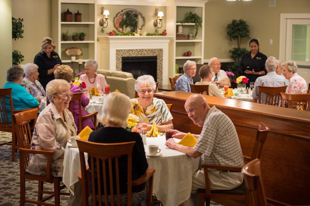 A group of seniors enjoying a meal together in a community dining setting.