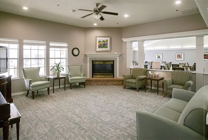 A cozy living room with a fireplace, ceiling fan, and comfortable seating.