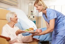 A nurse delivering a meal to a patient in a hospital.