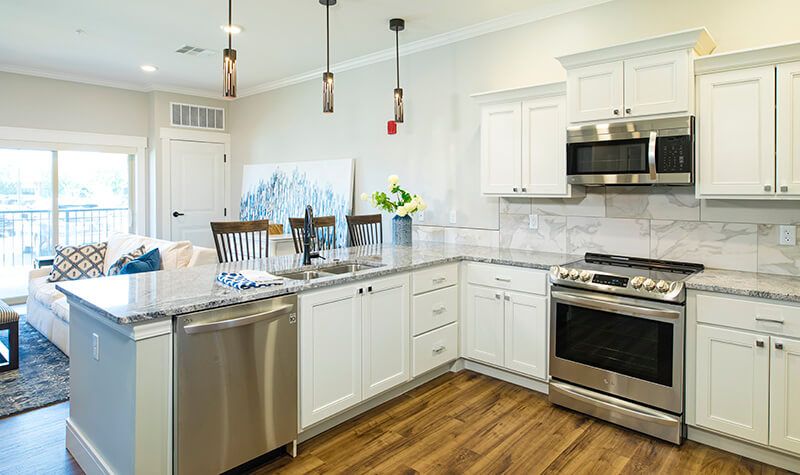 A modern kitchen with white cabinets, stainless steel appliances, and granite countertops.