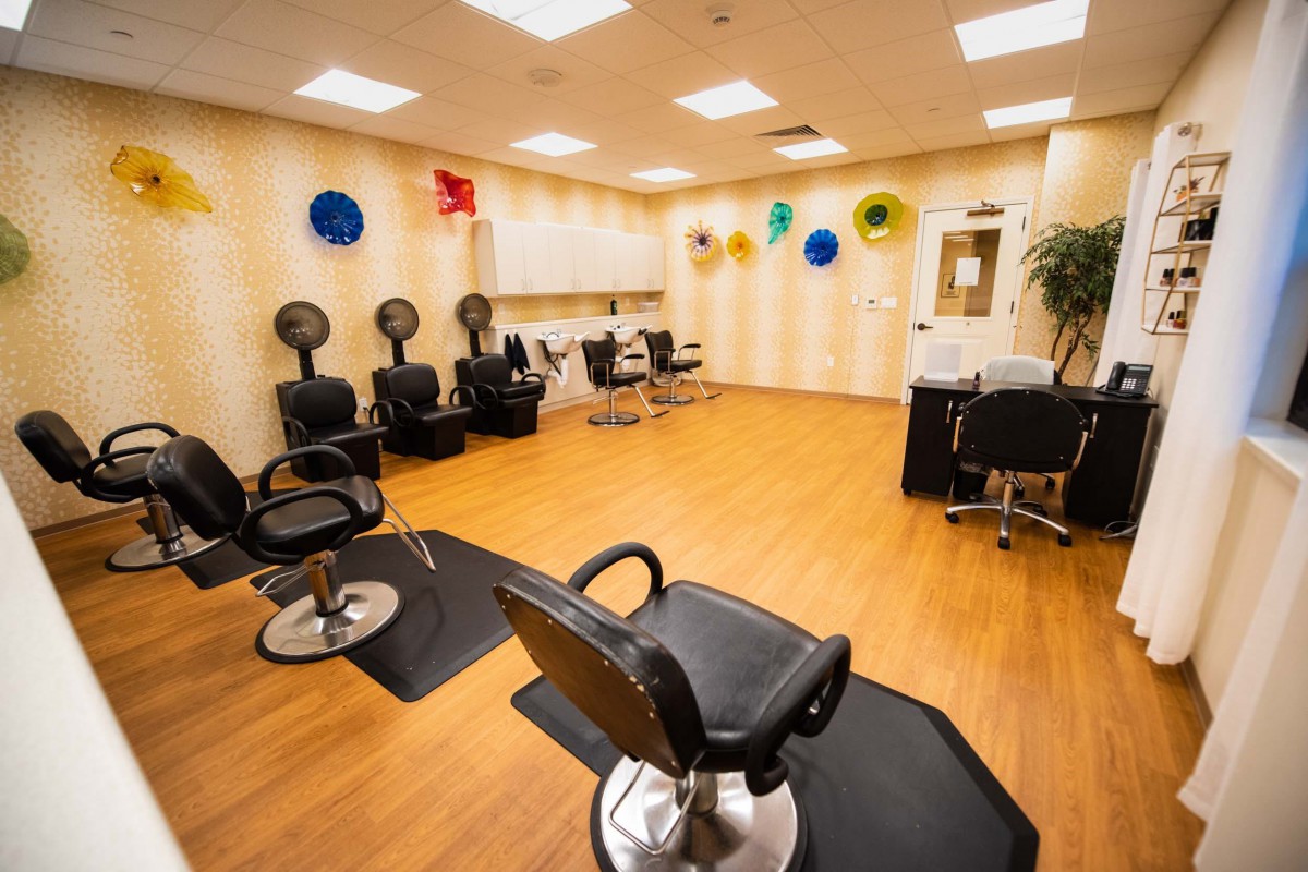 A neatly arranged hair salon with styling chairs, dryers, and colorful wall decor.