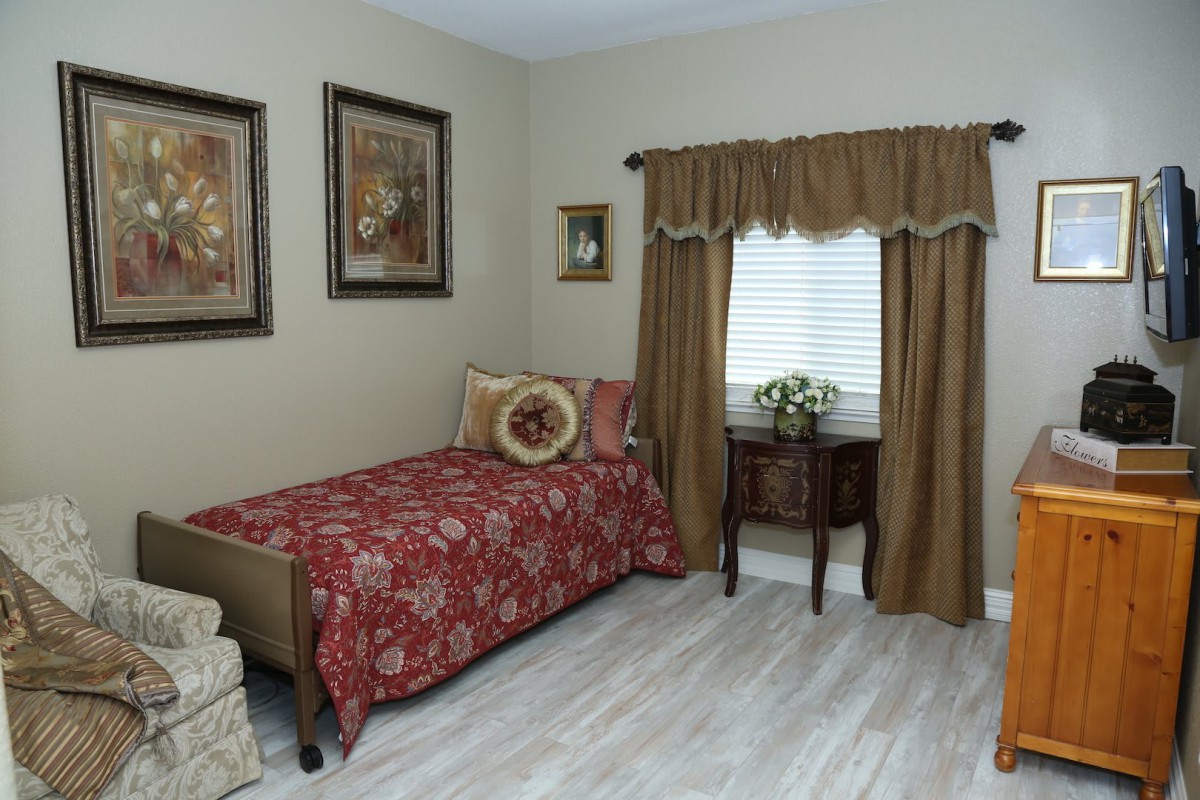 A cozy bedroom with a single bed, decorative pillows, side table, and wall art.