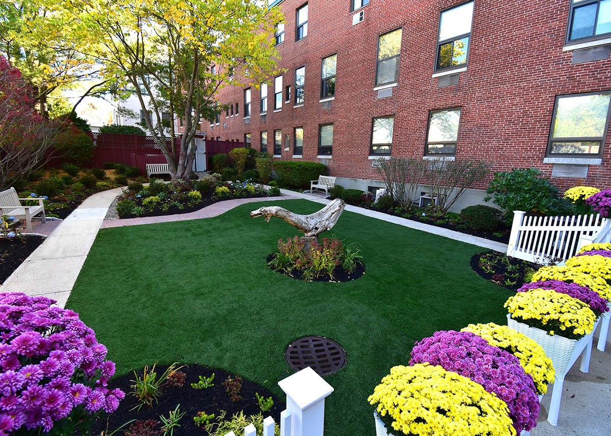 A beautifully landscaped garden with colorful flowers and lush greenery in front of a brick building.