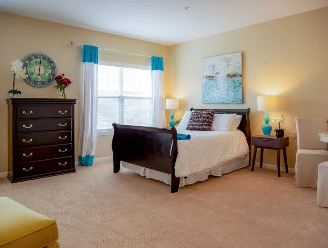 A cozy and elegantly decorated bedroom with a large bed, two bedside tables, lamps, and vibrant accents.