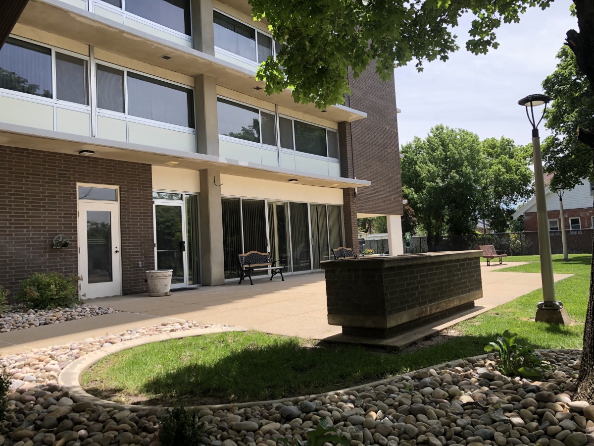 A modern apartment building with a patio and landscaped surroundings.