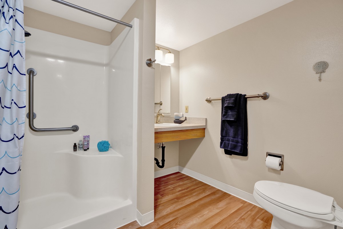 A modern bathroom interior featuring a shower, sink, and toilet with a towel rack.