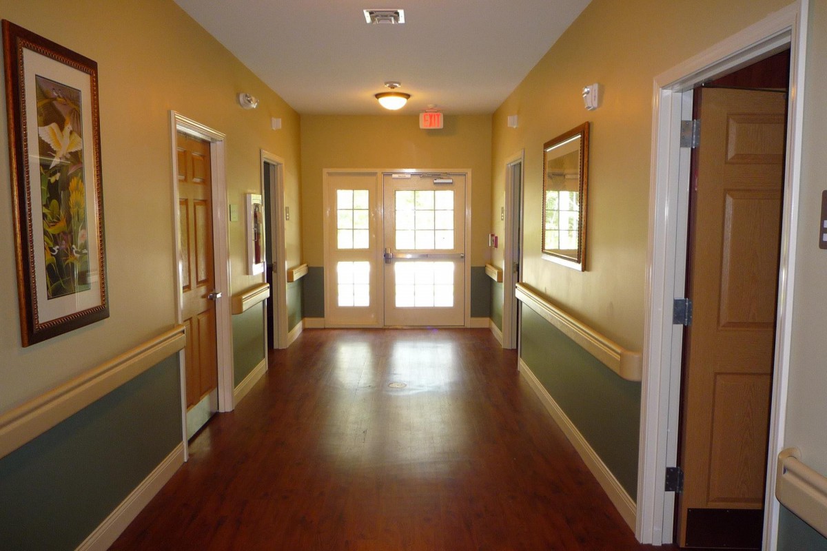 A well-lit hallway with wooden floors and two doors at the end.
