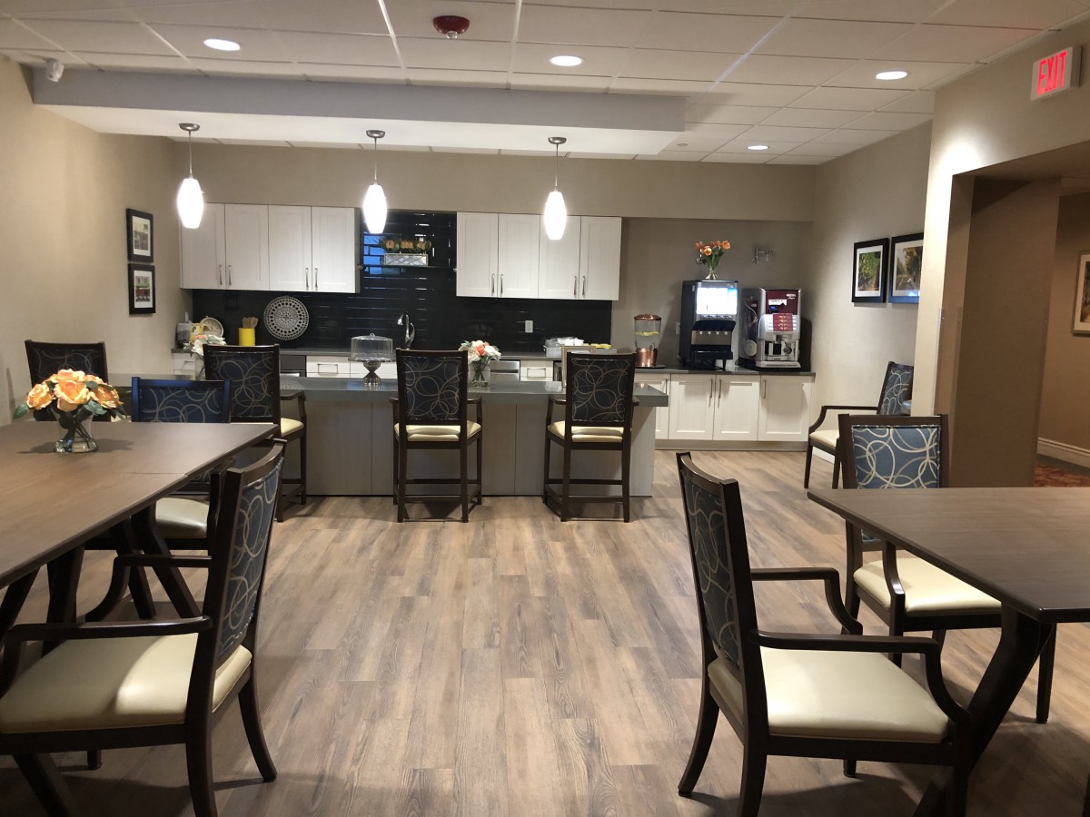 A modern kitchen and seating area with tables, chairs, and pendant lighting.