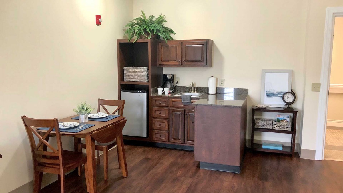 A cozy kitchenette with wooden cabinets, a mini fridge, and a small dining area.