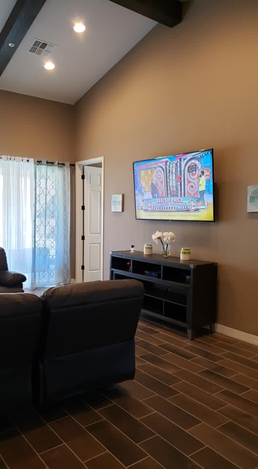 A cozy living room with a television mounted on the wall and comfortable seating.