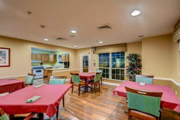A cozy dining room with tables and chairs, adjacent to a kitchen area.