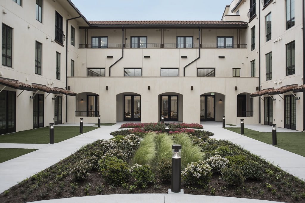 A courtyard with a landscaped garden surrounded by a multi-story building.