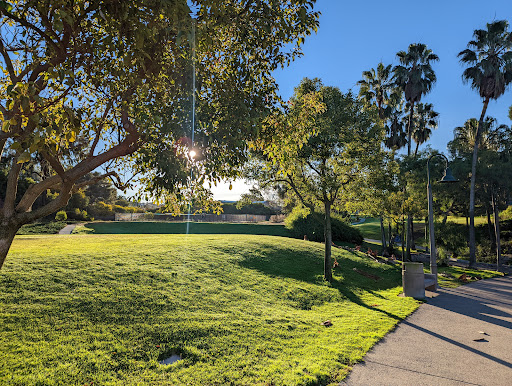 A serene park scene featuring lush greenery and a pathway under the sun.